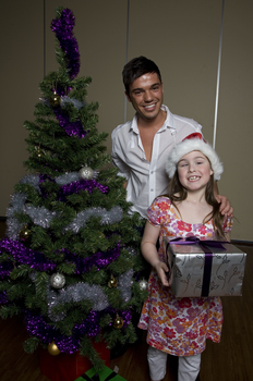 Kate Law with Anthony Callea holding a present next to a Christmas tree