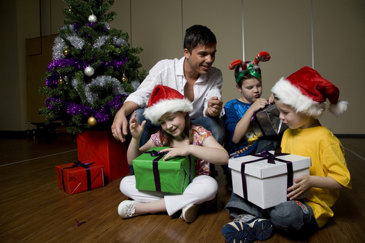 Kate, Nicholas and Jacob Law with Anthony Callea and presents under a Christmas tree