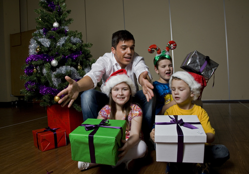 Kate, Nicholas and Jacob Law with Anthony Callea and presents under a Christmas tree