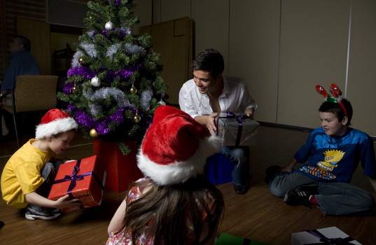 Kate, Nicholas and Jacob Law with Anthony Callea and presents under a Christmas tree