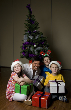 Kate, Nicholas and Jacob Law with Anthony Callea and presents under a Christmas tree