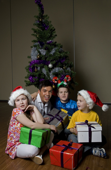 Kate, Nicholas and Jacob Law with Anthony Callea and presents under a Christmas tree