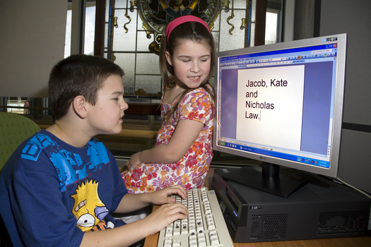 Nicholas Law using a computer in the Browsing Library with his sister Kate and Heidi Rogers looking on