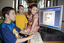 Nicholas Law using a computer in the Browsing Library with his sister Kate, brother Jacob and Heidi Rogers looking on