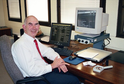 John Landau sitting at his desk with his computer and screen magnifier