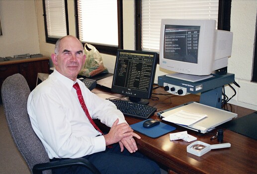 John Landau sitting at his desk with his computer and screen magnifier