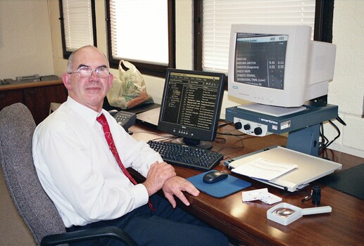 John Landau sitting at his desk with his computer and screen magnifier