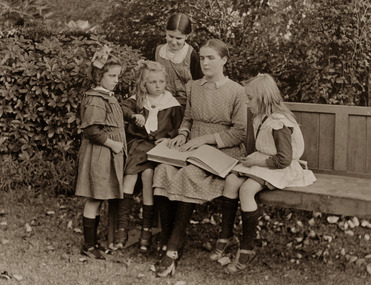 Older girl reading to younger girls from a Braille book