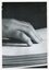 Hands reading a Braille page against dark background