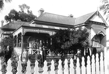 Weatherboard house with people in garden and on porch