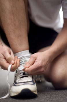 Male tying up laces on his running shoe