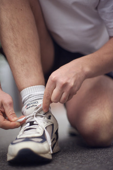 Male tying up laces on his running shoe