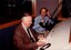 Bud Tingwell sits at the presenters desk with an announcer beside him