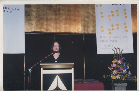 Narrator Kate Hosking reads at the podium