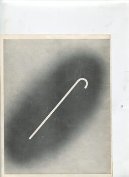 White cane on darkened background on white page