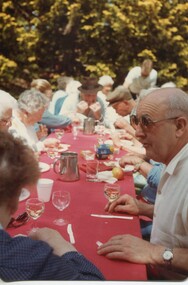 People eating lunch around a long table outside