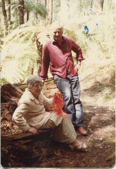 Lady rests on a tree log whilst a male sits with her