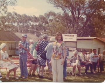 Group of people seated on chairs outside a track TAB