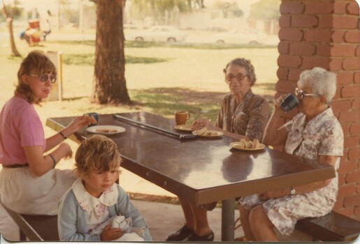 A young woman, child and two elderly woman sit at a table