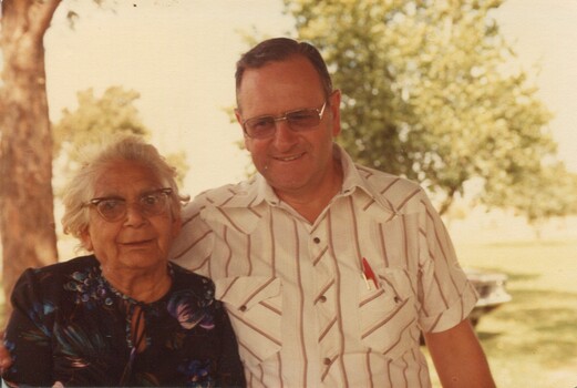An older woman and a staff member look towards camera