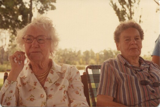 Two seated woman beside an unknown lake