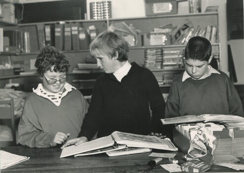 Three schoolboys reading print braille books in the library