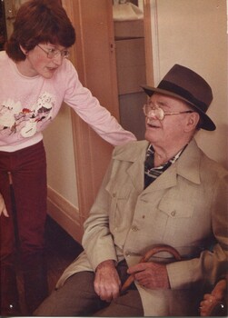 Man sits in corridor with woman speaking to him