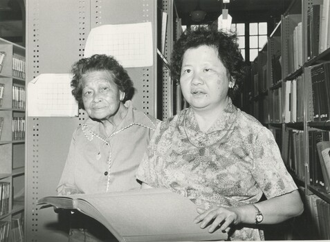 Two older women, one holding an open Braille book