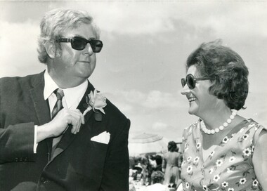 Noel Ferrier angles his flower towards a female at an outdoor event