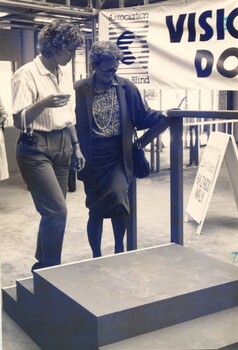 Blindfolded Hazel Hawke is accompanied by a mobility instructor as she mounts steps