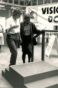 Blindfolded Hazel Hawke is accompanied by a mobility instructor as she mounts steps