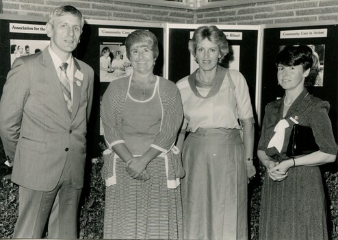 Four people stand in front of boards showing AFB activities