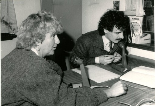 Caroline Hogg and a man speaking to microphones on a table