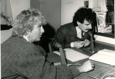 Caroline Hogg and a man speaking to microphones on a table