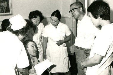 Group of nurses surround a man in a wheelchair