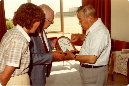 Three people examine a mantel clock