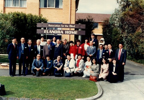 27 people stand underneath 'Elanora Home' sign