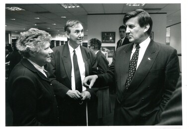 Two men and one woman chat in a busy room