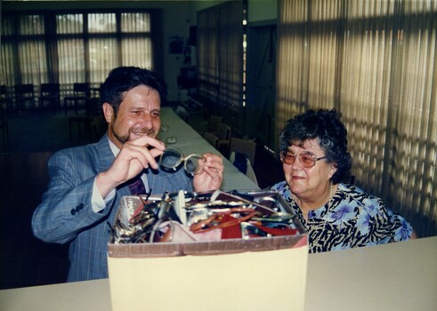 Nick Martinelli and Leslie Kingsford stand next to a box full of spectacles