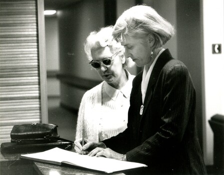 Woman signing in guest book with another beside her