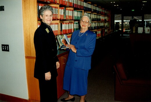 Dame Elisabeth Murdoch holds a copy of her biography with Marj West standing beside her