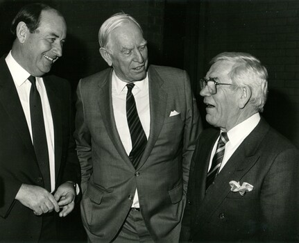 Three man talking as they stand dressed in suits and ties