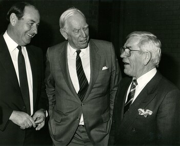 Three man talking as they stand dressed in suits and ties