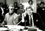 Mal Walden on telephone with cake in front of him and people singing