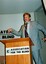 Max Walker addressing the audience from the podium with elaborate gestures