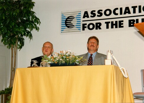 Max Walker sits at a table on the stage with possibly his father Max Walker