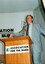 Max Walker addressing the audience from the podium with elaborate gestures