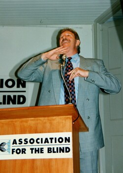 Max Walker addressing the audience from the podium with elaborate gestures