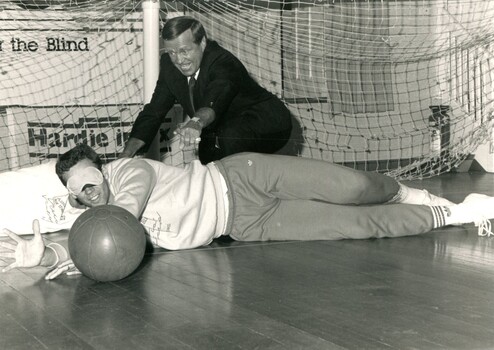 Blinded peron stops a ball whilst Ted Whitten reaches for it