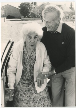 Elderly female assisted by male from car